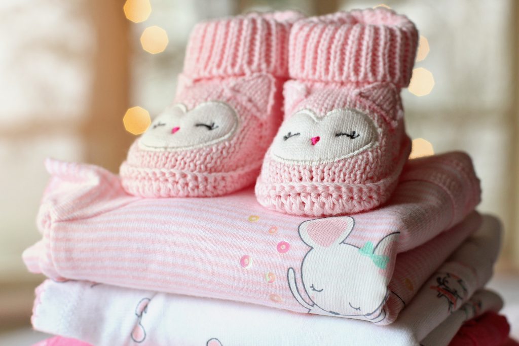 Chaussons de couleur rose avec un motif de chouettes posés sur des vêtement pour fille